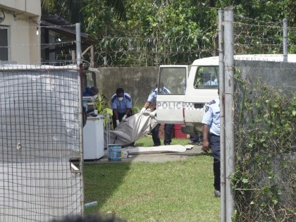Police pull one of the bodies into the back of a police van 